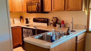 A kitchen with wooden cabinets, a built-in microwave, a stove, and a sink.