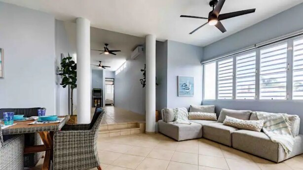 A spacious living area with a sofa, a dining table with chairs, and a ceiling fan. - Parguera Paradise, Luxury Modern Beach House! (Lajas)