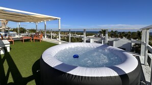 An outdoor hot tub with a clear view of the ocean and a patio area with seating. - Parguera Paradise, Luxury Modern Beach House! (Lajas)