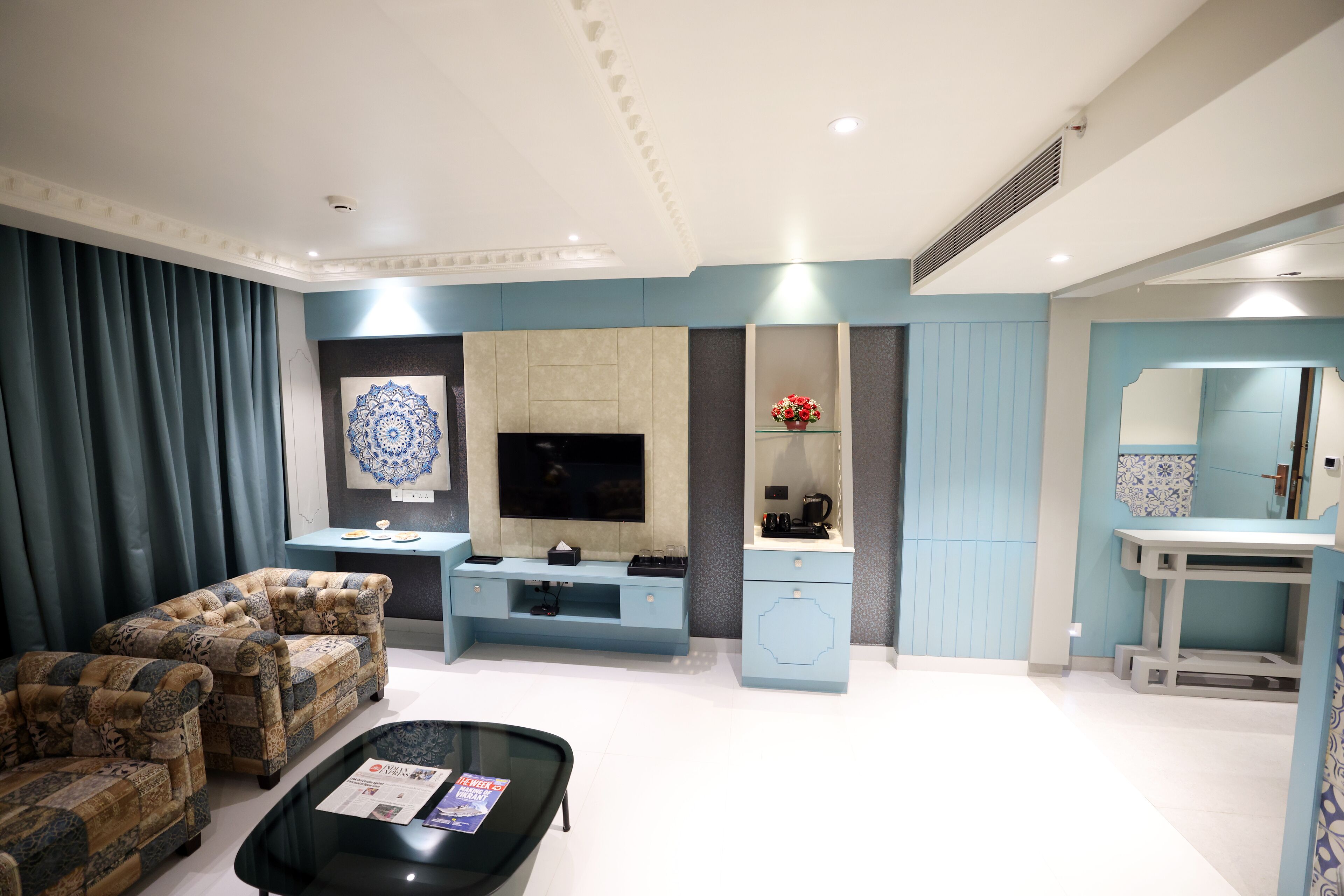Una sala de estar moderna con sofá, mesa de centro, televisor y una pequeña área de cocina con pileta y mostrador.