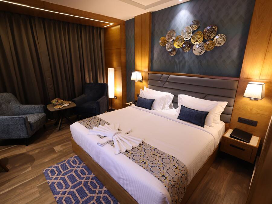 Habitación de hotel con una cama grande, dos mesitas de noche, un escritorio, una silla y un adorno en la pared.