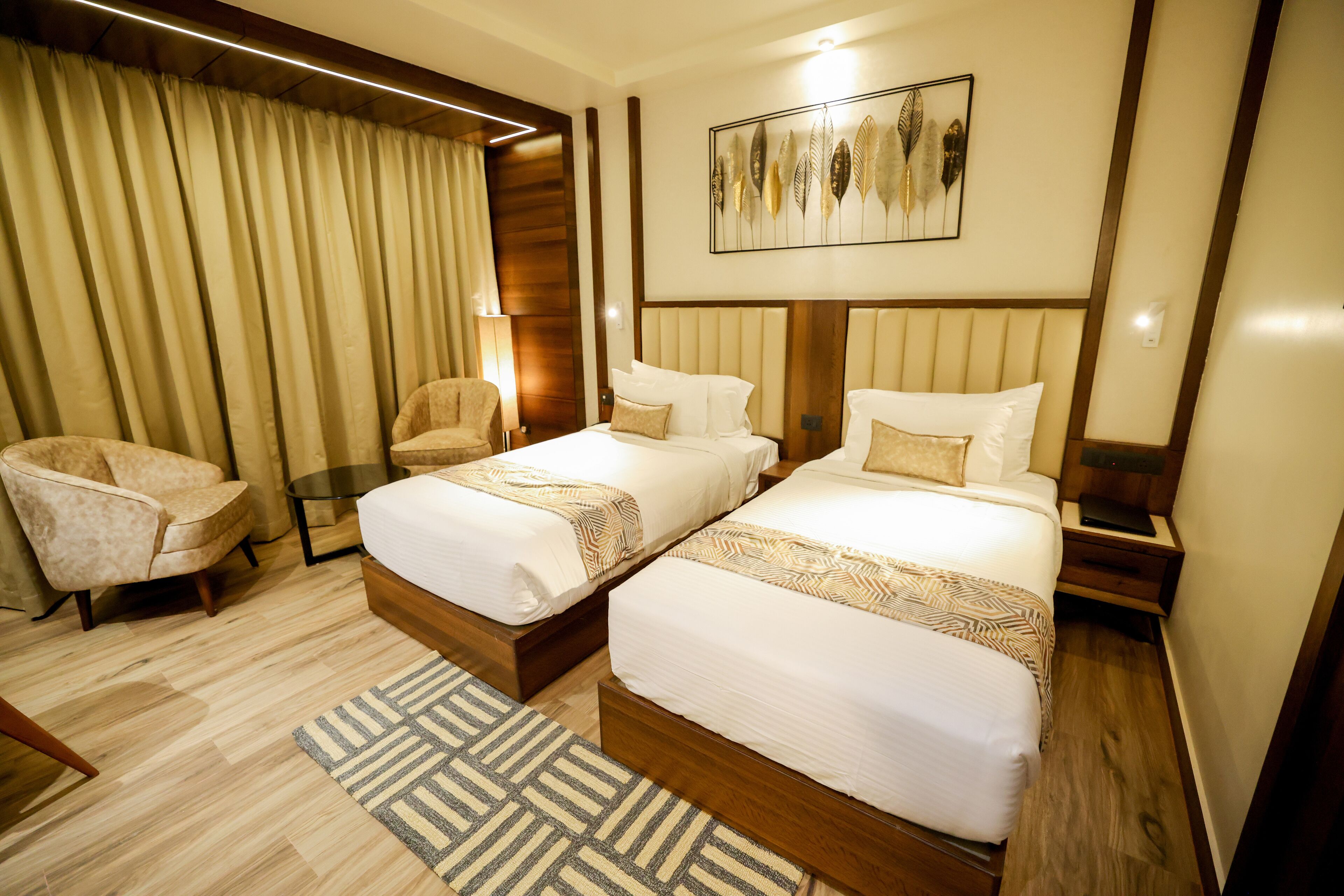 A hotel room with two beds, a sofa, a lamp, and a decorative wall piece.