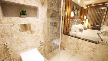 A modern bathroom with a glass shower enclosure, a marble sink, and a built-in shelf with a plant.