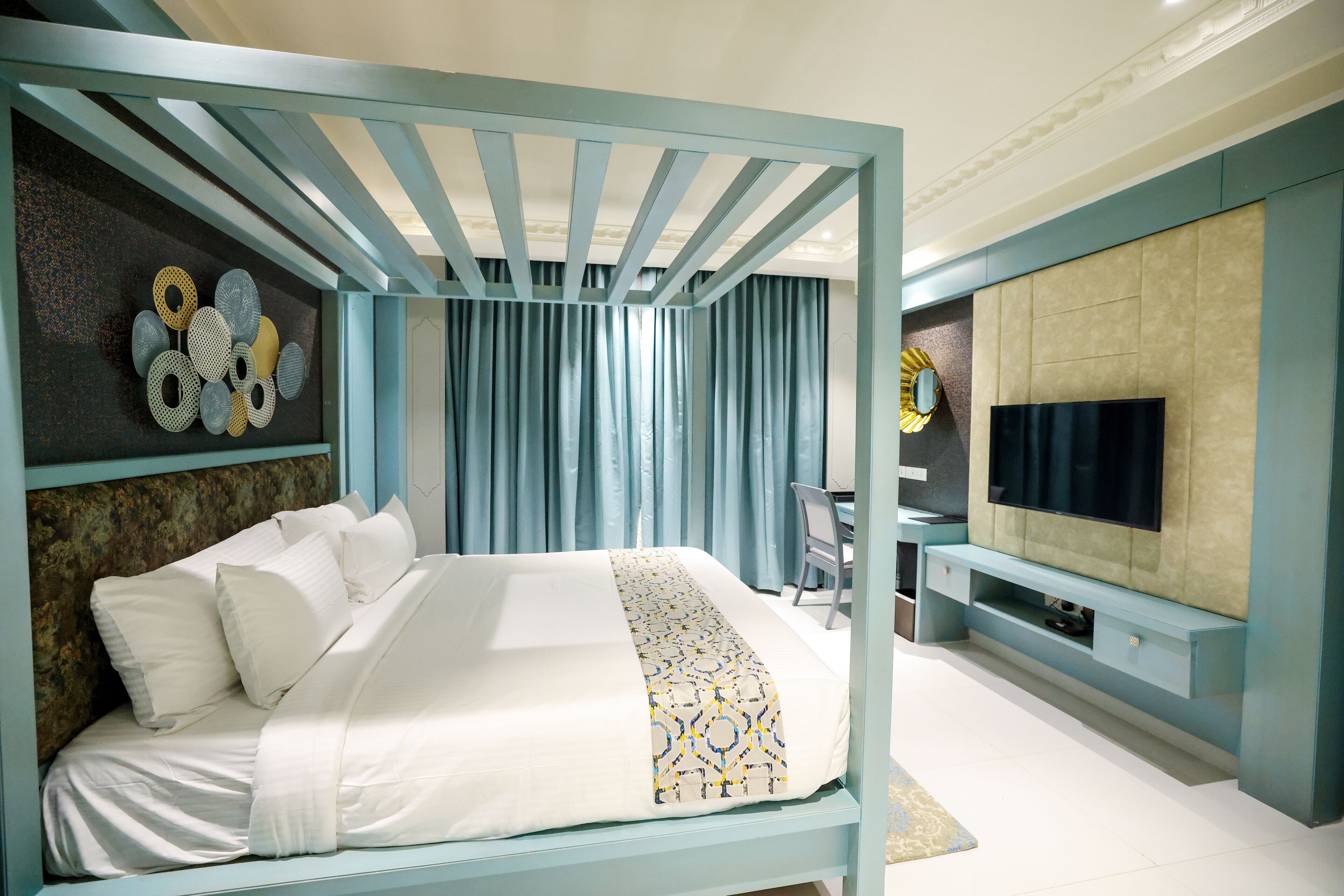 A modern bedroom with a bed, a TV, and a desk.