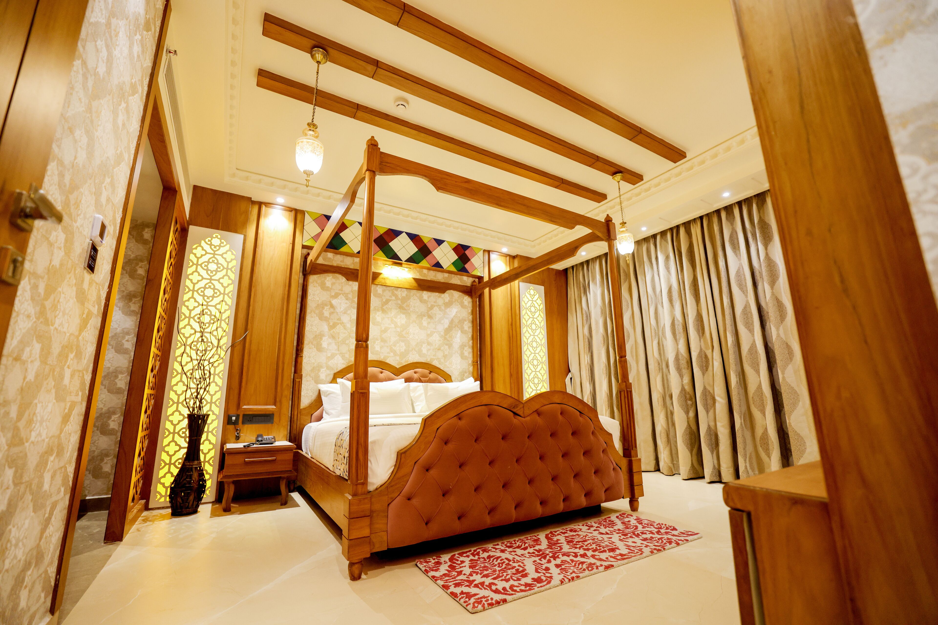 A four-poster bed with a wooden frame and tufted headboard, a bedside table, and a nightstand.