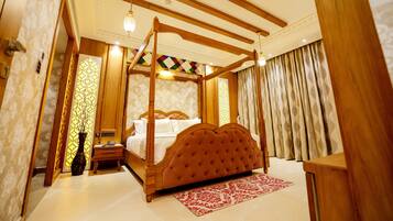 A four-poster bed with a wooden frame and tufted headboard, a bedside table, and a nightstand.