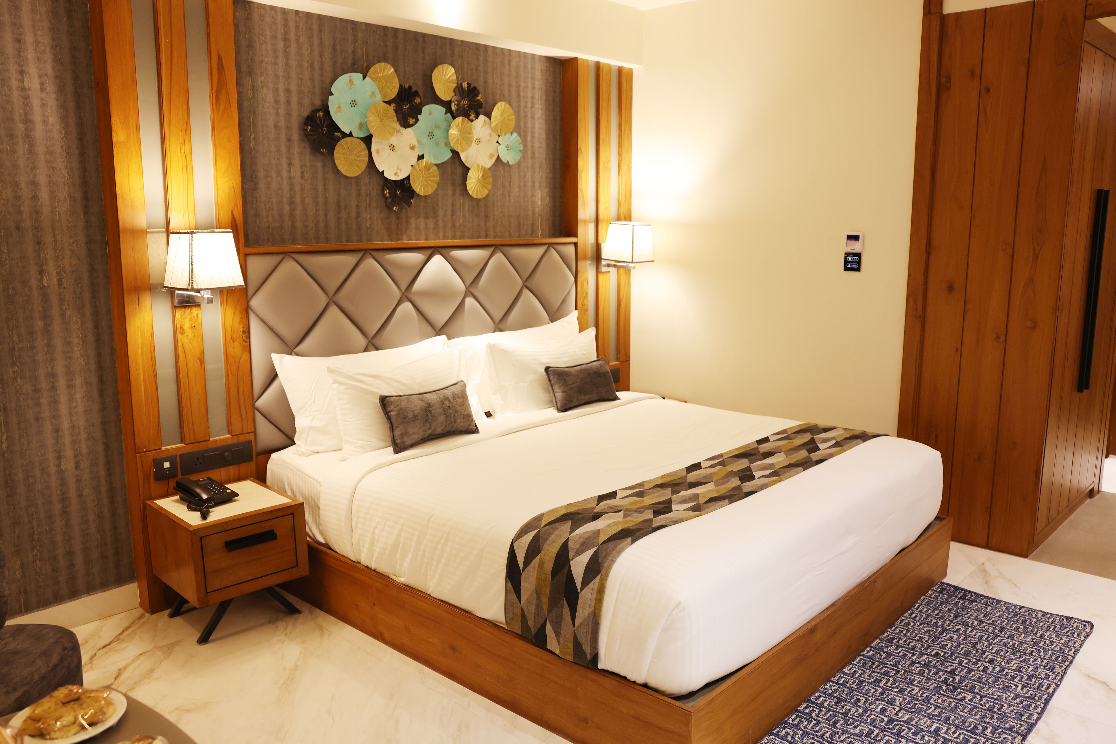 A neatly made bed with a patterned bedspread, a wooden headboard, and two bedside lamps.