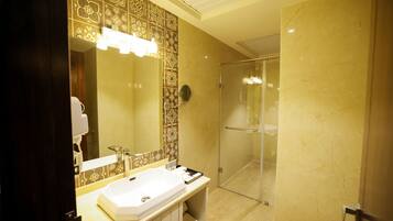 Une salle de bain avec un grand miroir, un lavabo et un espace douche.