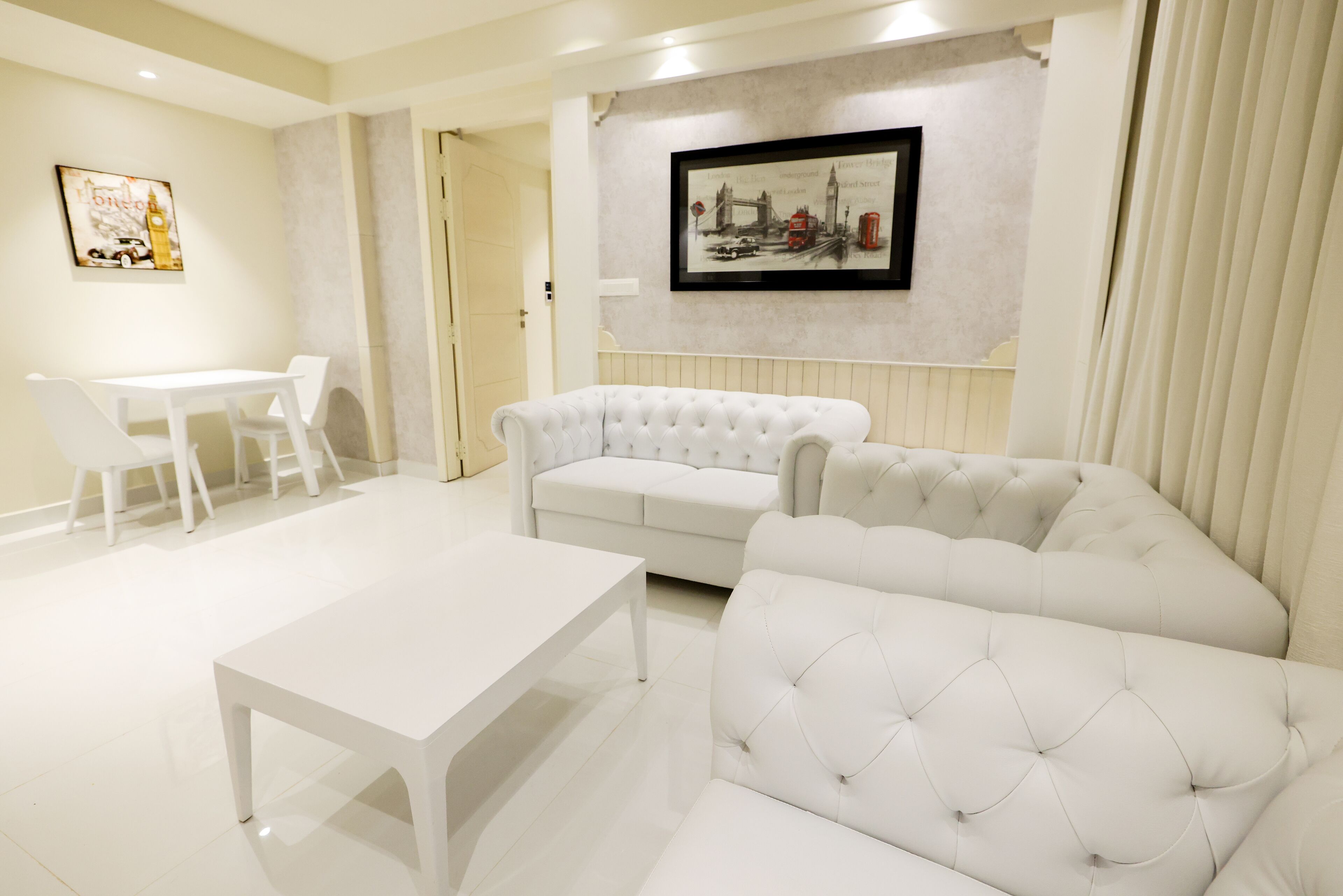 Een moderne woonkamer met een witte bank, een witte tafel en een ingelijst kunstwerk aan de muur.