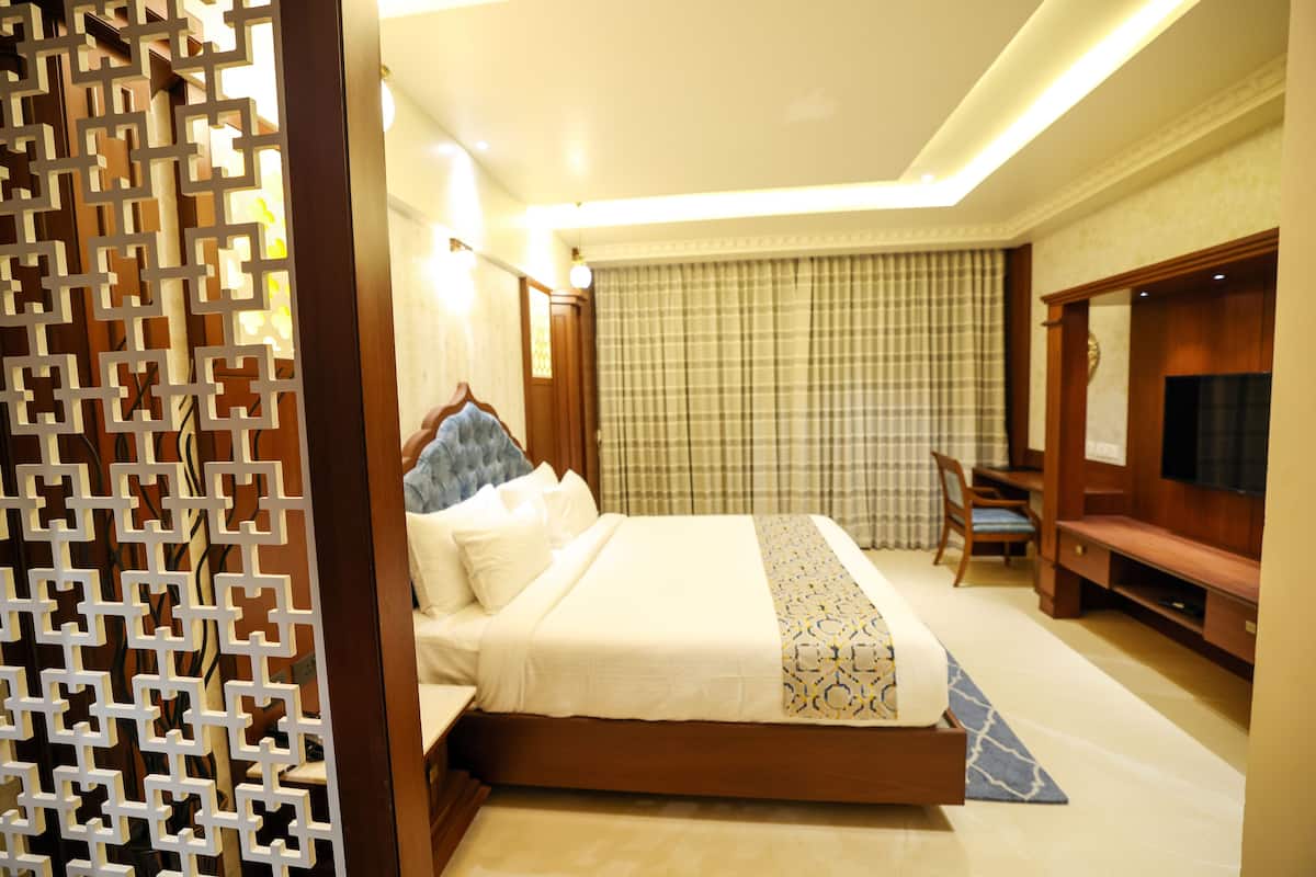 A hotel room with a bed, a desk, a chair, and a TV.