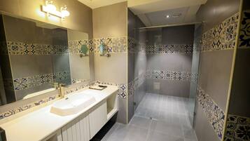 Un baño con lavamanos doble, espejo y zona de ducha con azulejos estampados.