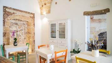 Un comedor con pared de piedra, armarios blancos y chimenea.