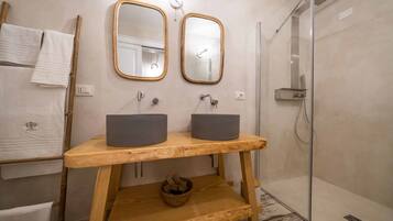 Un baño con dos lavamanos, tocador de madera, espejos y ducha.