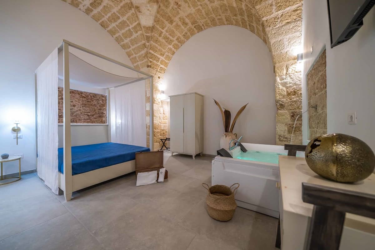Ein Zimmer mit Bett, Badewanne, Schrank und einer Steinwand.