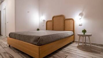 Une chambre moderne avec un lit en bois, deux lampes fixées au mur et une petite table ronde sur laquelle est posé un vase vert.