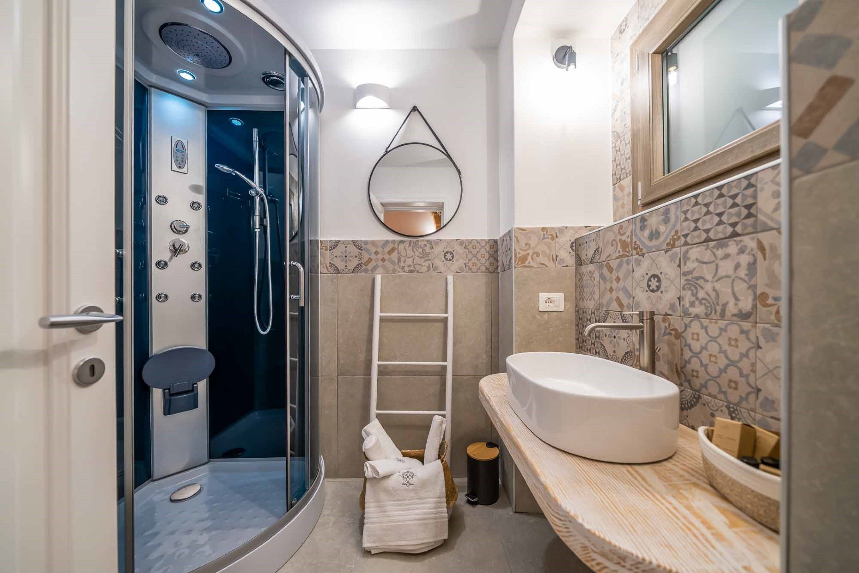 Un baño moderno con ducha acristalada, lavabo blanco y salpicadero de azulejos.
