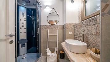 Un baño moderno con ducha acristalada, lavabo blanco y salpicadero de azulejos.