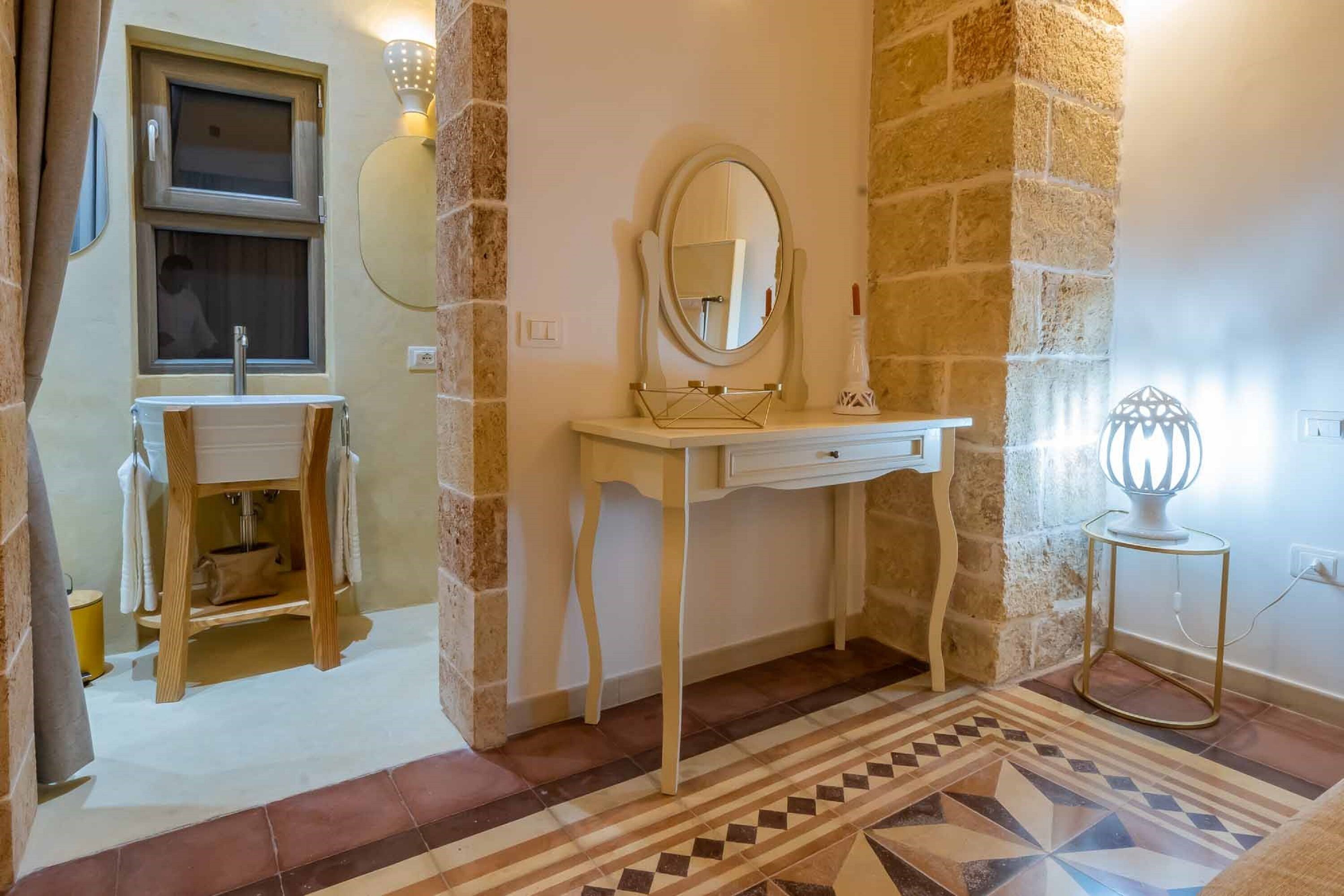 Un bagno con lavandino, specchio e mobile contenitore.