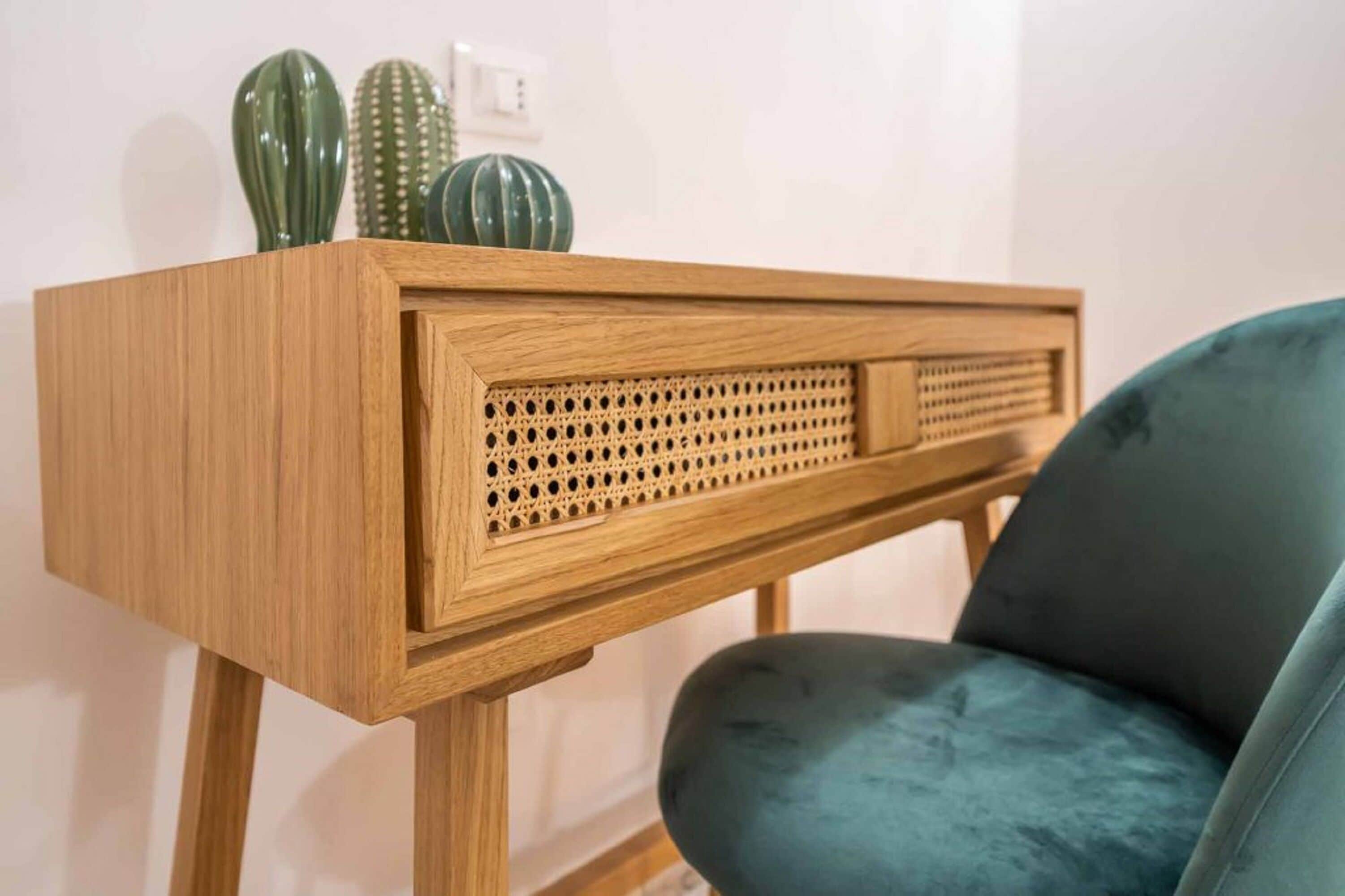 A wooden console table with a woven front panel, accompanied by a blue chair.