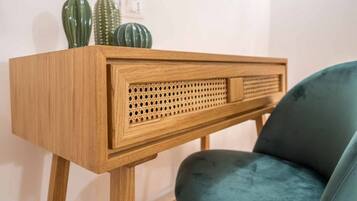 A wooden console table with a woven front panel, accompanied by a blue chair.