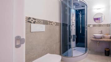 A modern bathroom with a glass-enclosed shower, a white toilet, and a sink with a marble countertop.