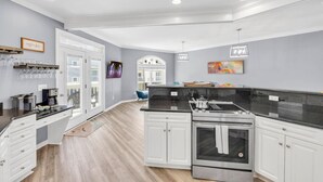 A modern kitchen with white cabinetry, a stainless steel stove, and a black countertop. - Starfish Retreat II  Walk to Carolina Beach (Carolina Beach)