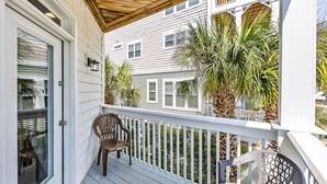 A covered porch with a white railing, a wooden ceiling, and a door with glass panels. - Starfish Retreat II  Walk to Carolina Beach (Carolina Beach)