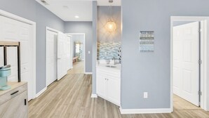 A hallway with white doors, a kitchen area with a tiled backsplash, and a pendant light. - Starfish Retreat II  Walk to Carolina Beach (Carolina Beach)