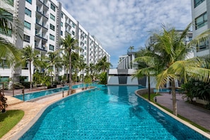 A swimming pool surrounded by palm trees and modern buildings. - Pool Views De Luxe at Arcadia Beach Resort (Pattaya)