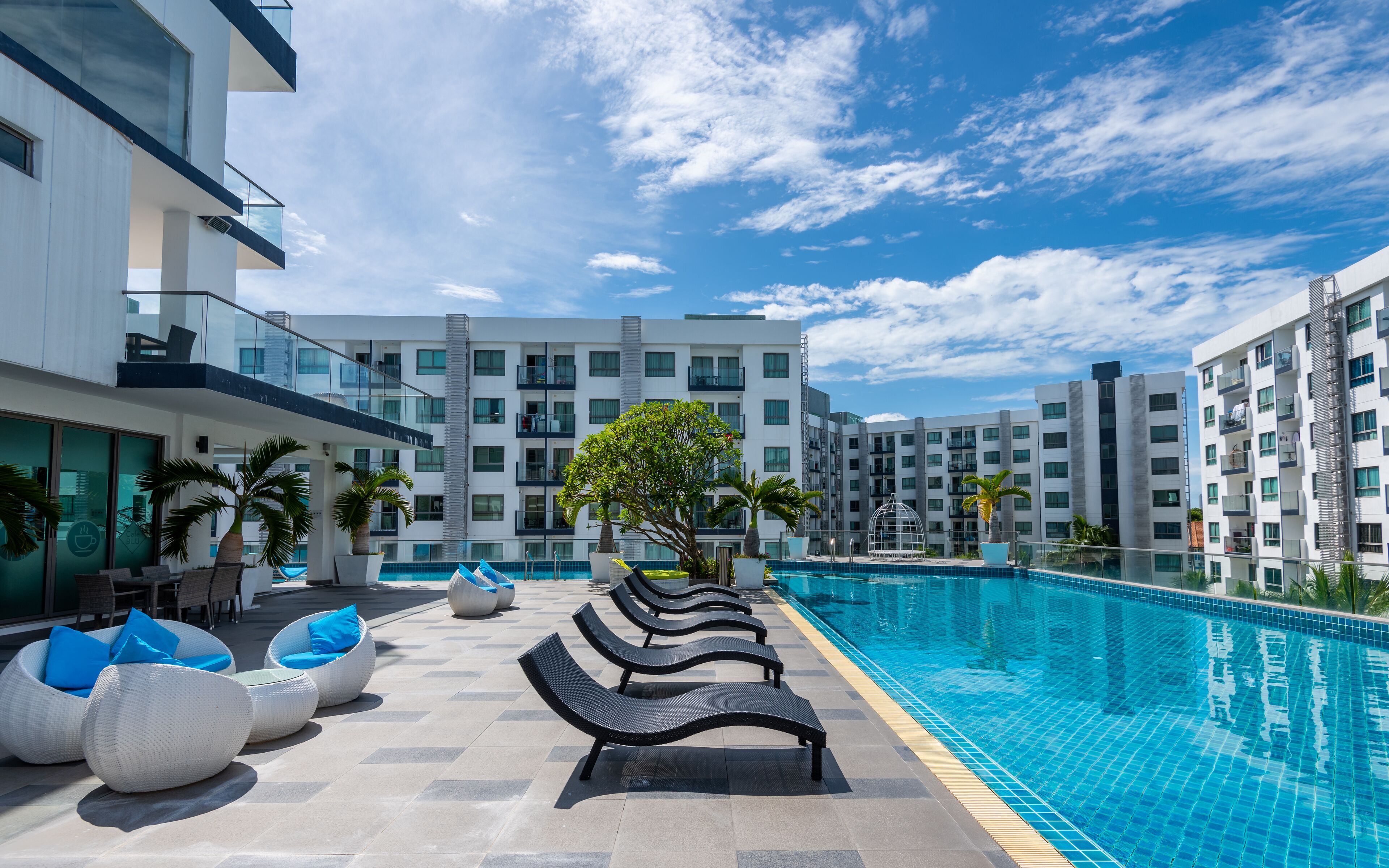 Un hôtel moderne doté d’une piscine, d’un espace extérieur aménagé et offrant une vue dégagée sur les bâtiments environnants.