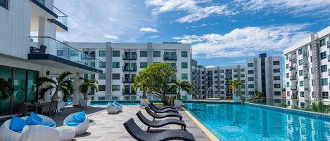 Un hôtel moderne doté d’une piscine, d’un espace extérieur aménagé et offrant une vue dégagée sur les bâtiments environnants.