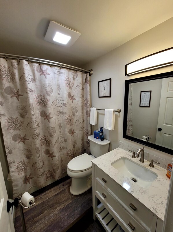 A bathroom with a toilet, sink, and shower curtain with sea life patterns.