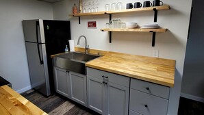 Cozinha moderna com armários cinza, bancada de madeira e prateleiras embutidas com copos e louças.