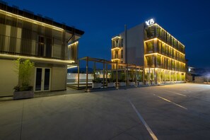 A modern hotel with a prominent 'XB' sign, featuring a glass facade, outdoor seating area, and a spacious courtyard. - X Business (Saviano)