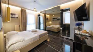 A modern hotel room with a large bed, a TV, and a bathroom with a mirror. - X Business (Saviano)