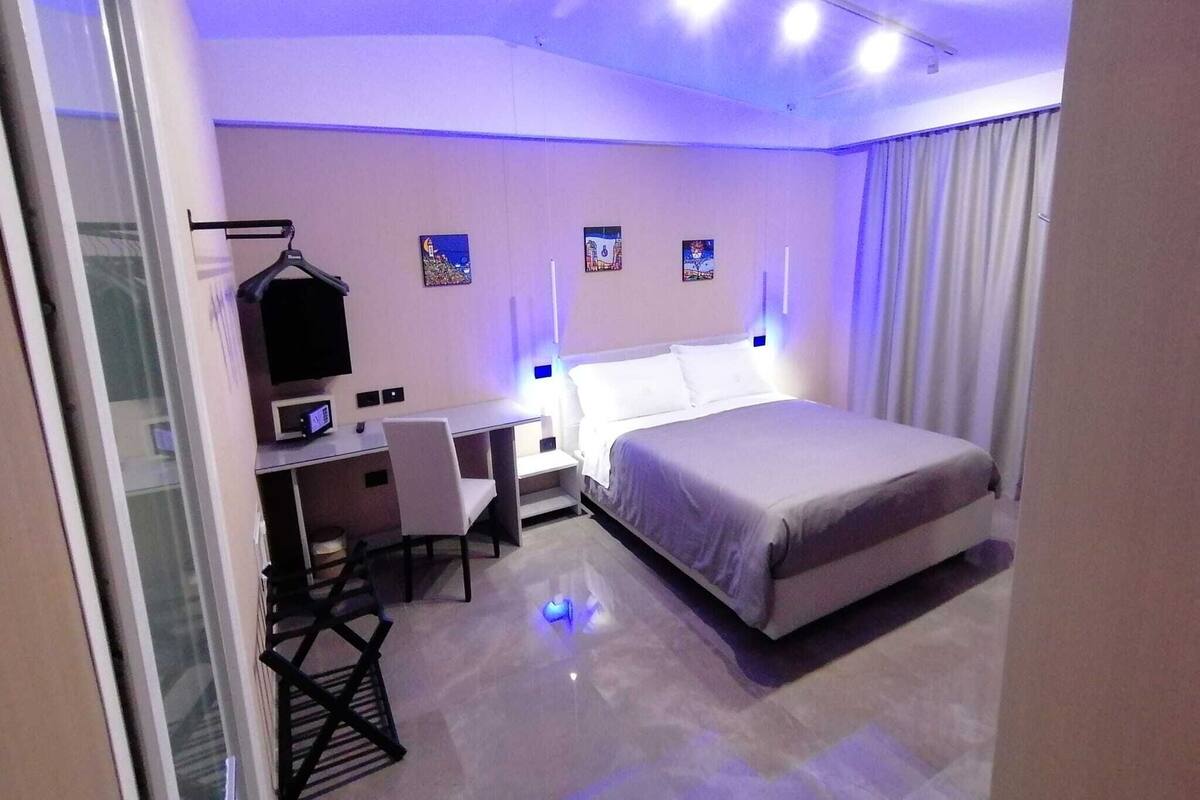 A modern hotel room with a bed, desk, chair, and a TV.