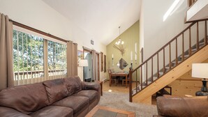 A living room with a brown leather sofa, a coffee table, and a staircase leading to another level. - Twin Rivers Vasquez 3 Perfect 3 Bedroom sleeps 9, private deck, river views (Fraser)