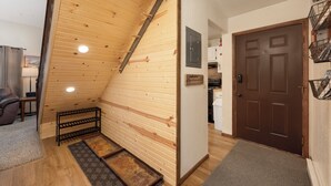 A wooden interior with a sloped ceiling, a brown door, and a kitchen area visible through an open doorway. - Twin Rivers Vasquez 3 Perfect 3 Bedroom sleeps 9, private deck, river views (Fraser)