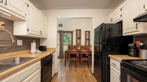 A kitchen with white cabinets, a black refrigerator, wooden dining table, and chairs. - Twin Rivers Vasquez 3 Perfect 3 Bedroom sleeps 9, private deck, river views (Fraser)