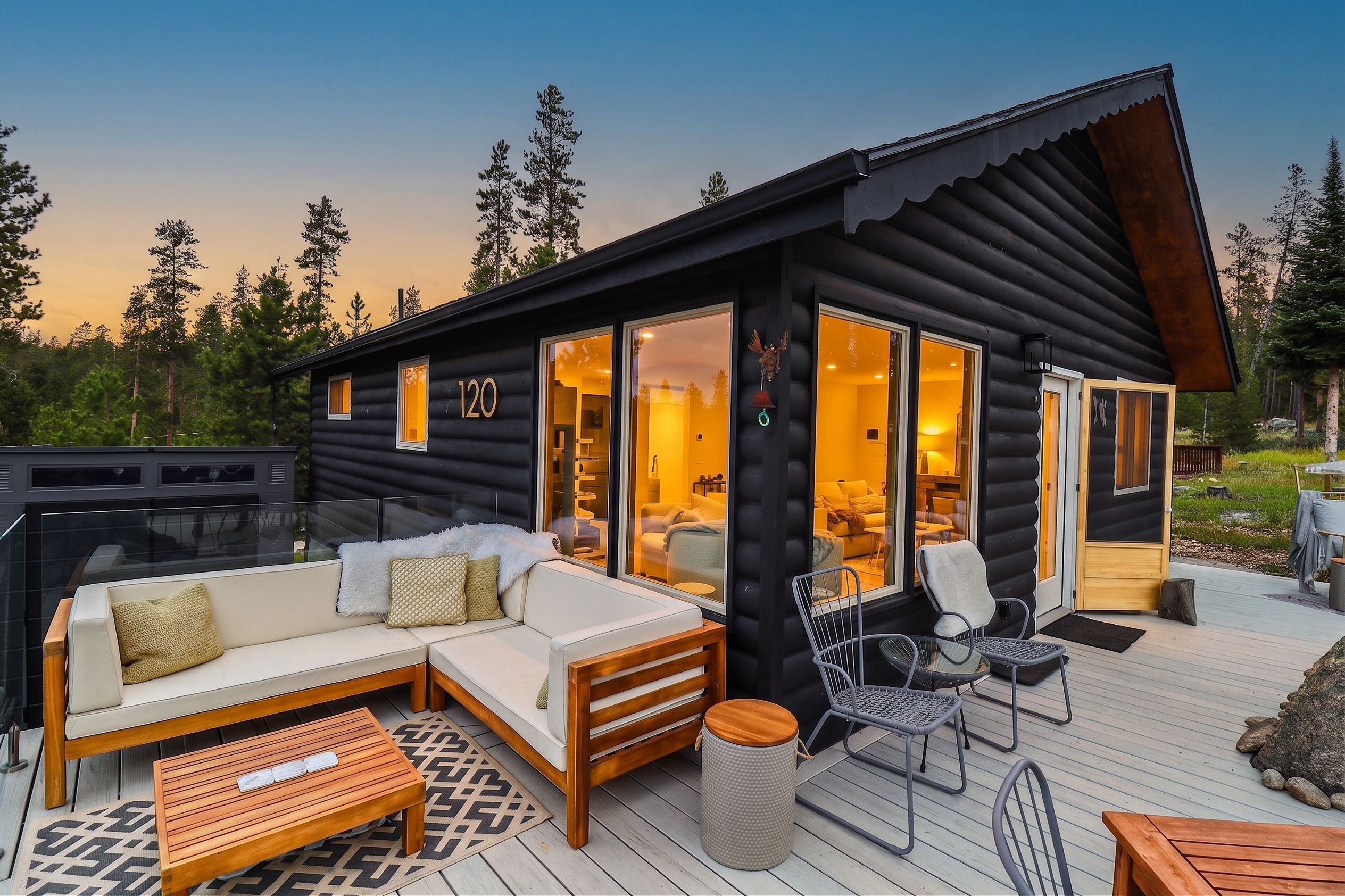 A log cabin with a deck, a sofa, and a chair.