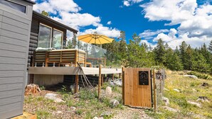 A modern log cabin with a deck and a yellow umbrella, surrounded by natural landscape. - BeeHive Bungalow - Gorgeous Lake views and completely updated throughout! (Grand Lake)