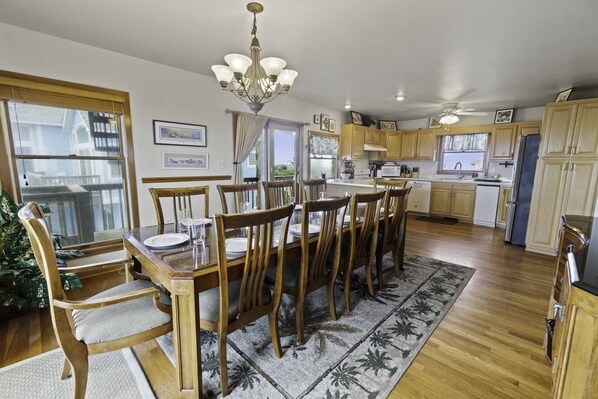 A spacious kitchen with wooden cabinets, a dining area with a large table and chairs, and a chandelier.