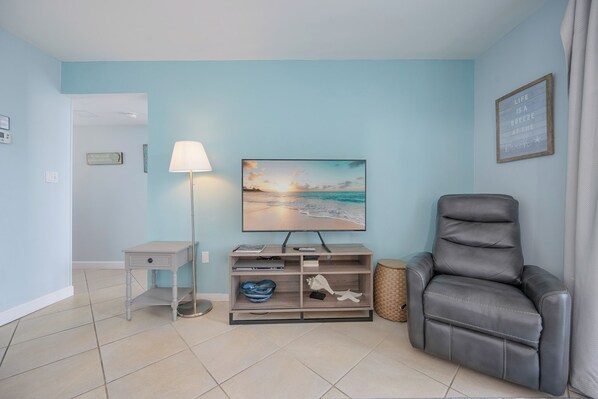 A room with a TV, a desk, a chair, and a lamp.