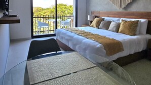 Ein modernes Schlafzimmer mit Bett, Glastisch, Deckenventilator und Blick ins Freie.