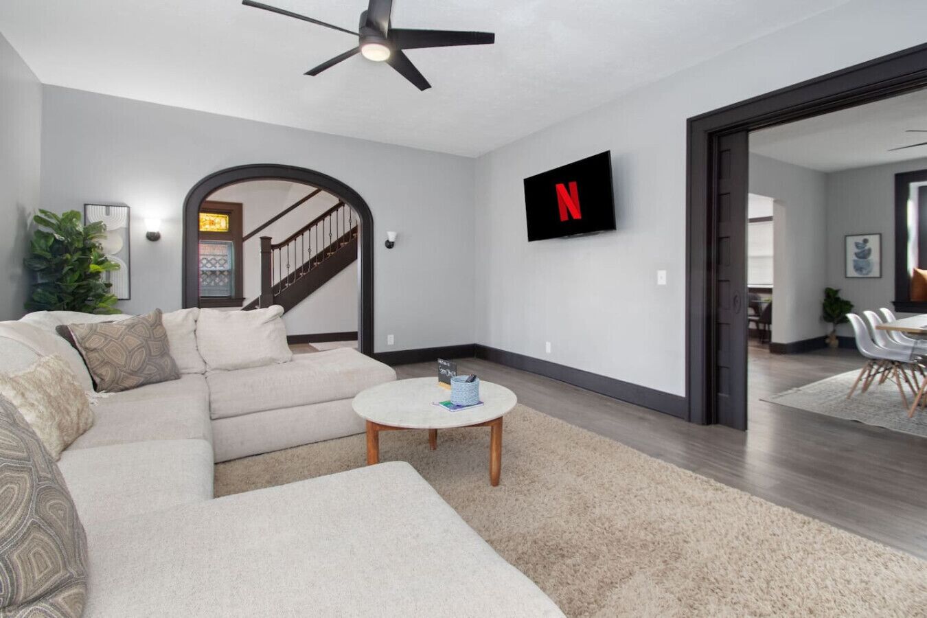 A modern living room with a sectional sofa, a round coffee table, and a ceiling fan.