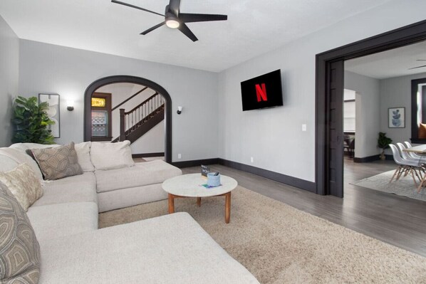 A modern living room with a sectional sofa, a round coffee table, and a ceiling fan.