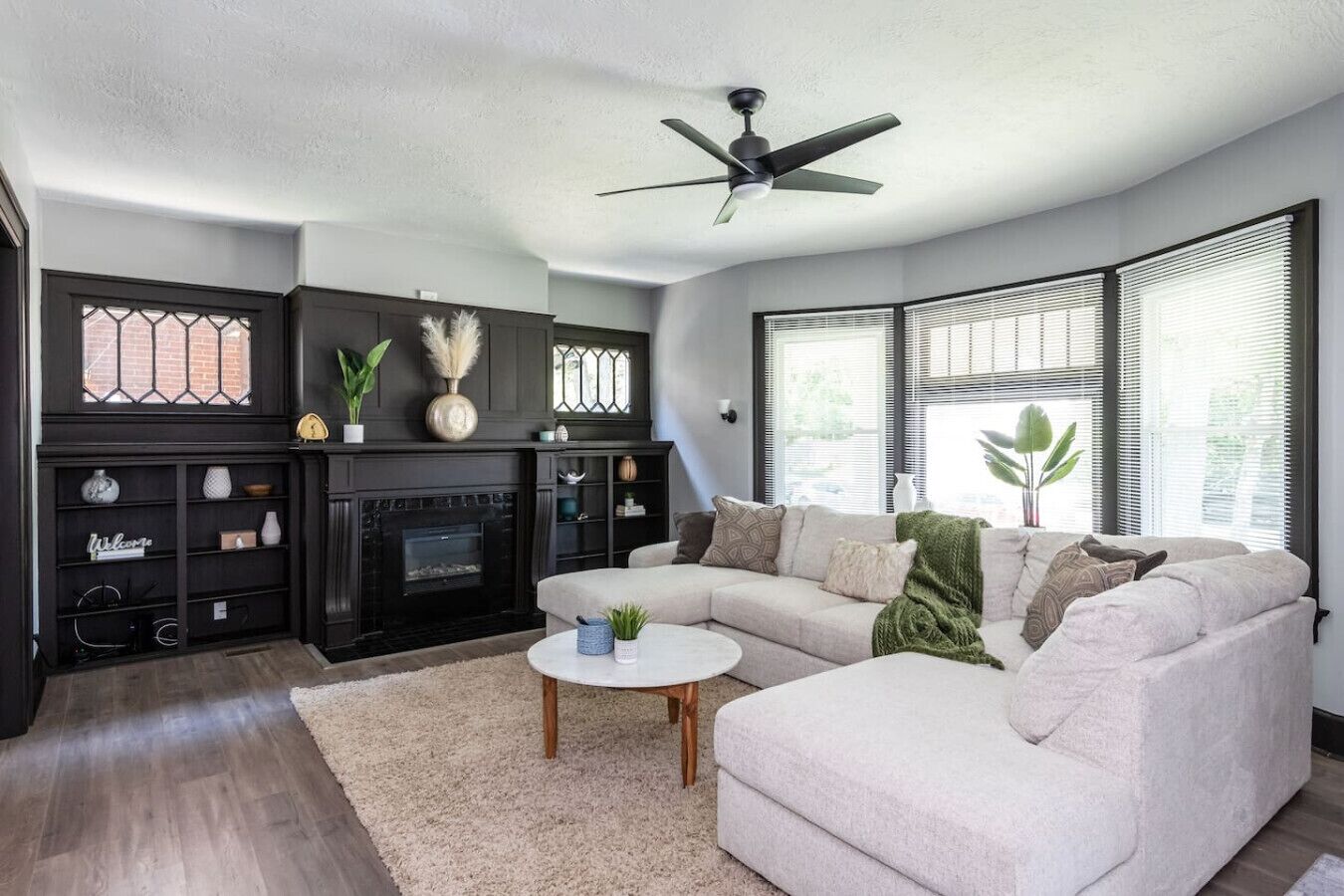 Un salon avec une cheminée, un canapé, une table basse et un ventilateur de plafond.