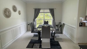 A dining room with a rectangular table, six chairs, and a window with curtains. - Beautiful Comfortable House w/ Fireplace (Woodstock)