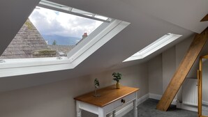 A room with a sloped ceiling and skylights, a wooden table, and a radiator. - Grisedale Pike -  a maisonette that sleeps 2 guests  in 1 bedroom (Central Keswick)