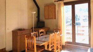 A cozy room with a wooden dining table, chairs, a cabinet, a television, and a large window with curtains. - 1st floor, tv, ski locker, 58m², Villard de Lans (Corrençon-en-Vercors)